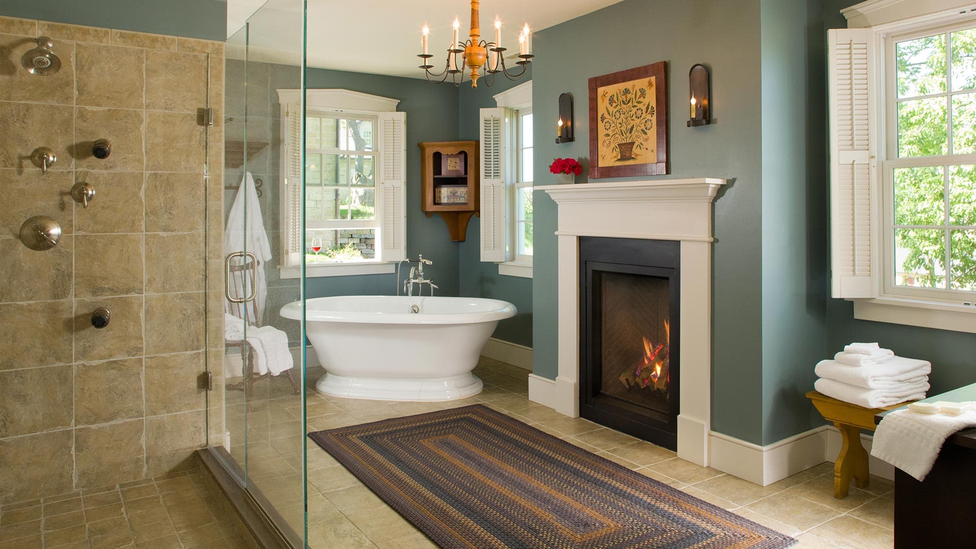A stylish bathroom featuring a freestanding tub, glass shower, and a cozy fireplace.
