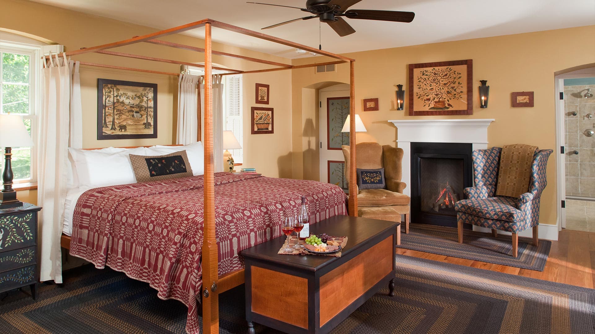 A cozy bedroom featuring a four-poster bed, decorative seating, and a fireplace.