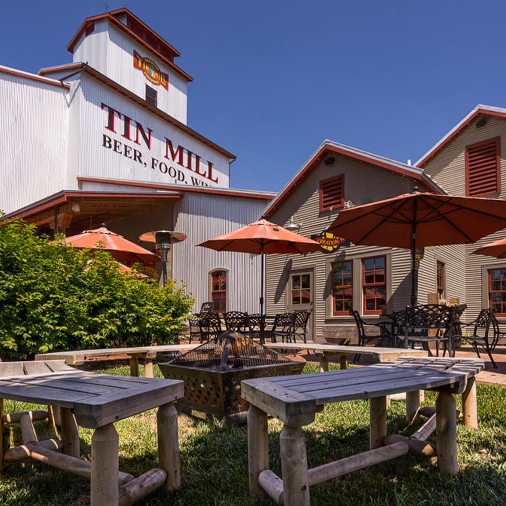 Exterior view of the Tin Mill restaurant featuring outdoor seating and umbrellas.