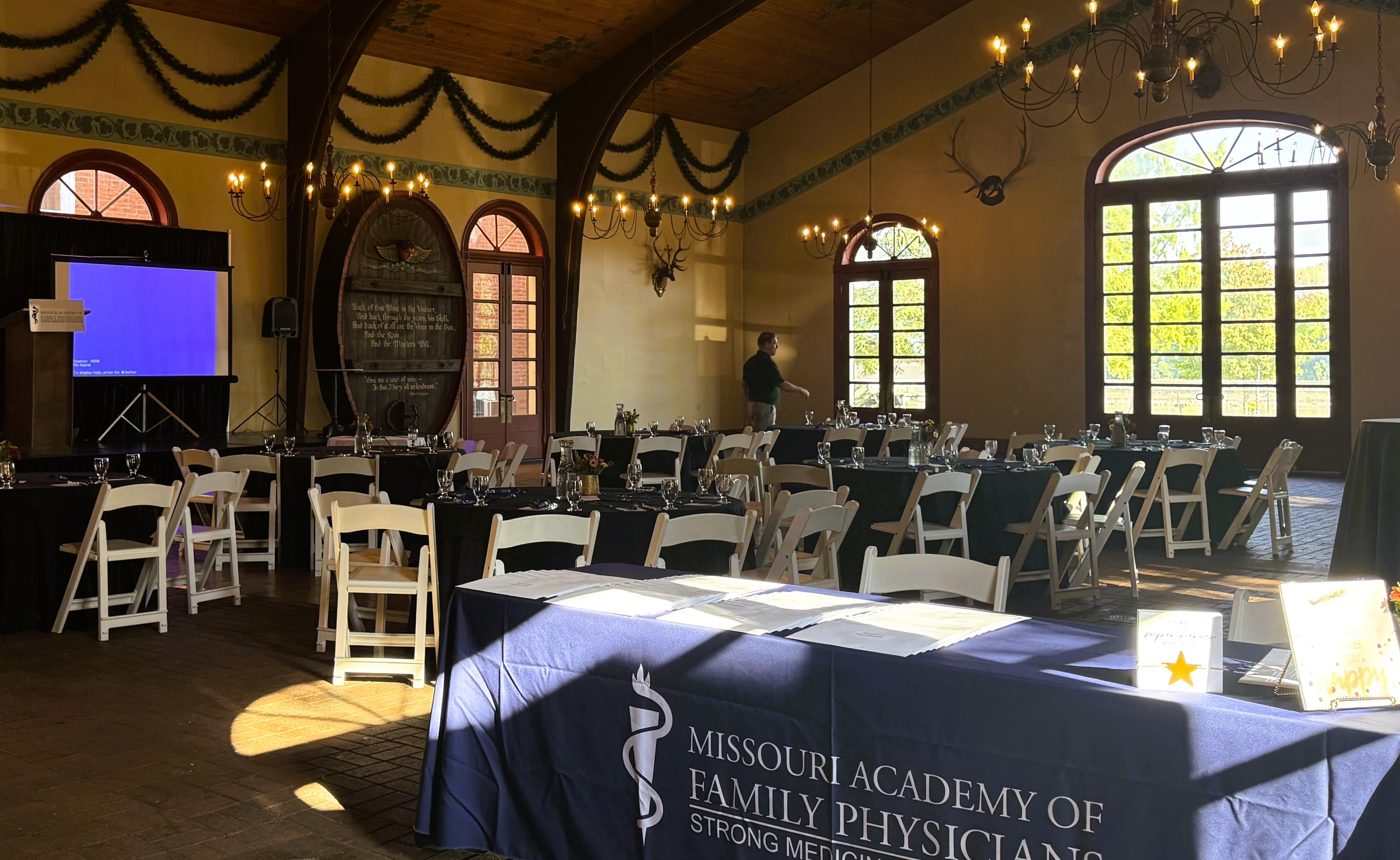 An elegantly arranged event space with tables set for dining, a podium, and a display for the Missouri Academy of Family Physicians.