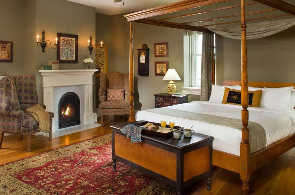 A cozy bedroom featuring a four-poster bed, a fireplace, and comfortable seating.