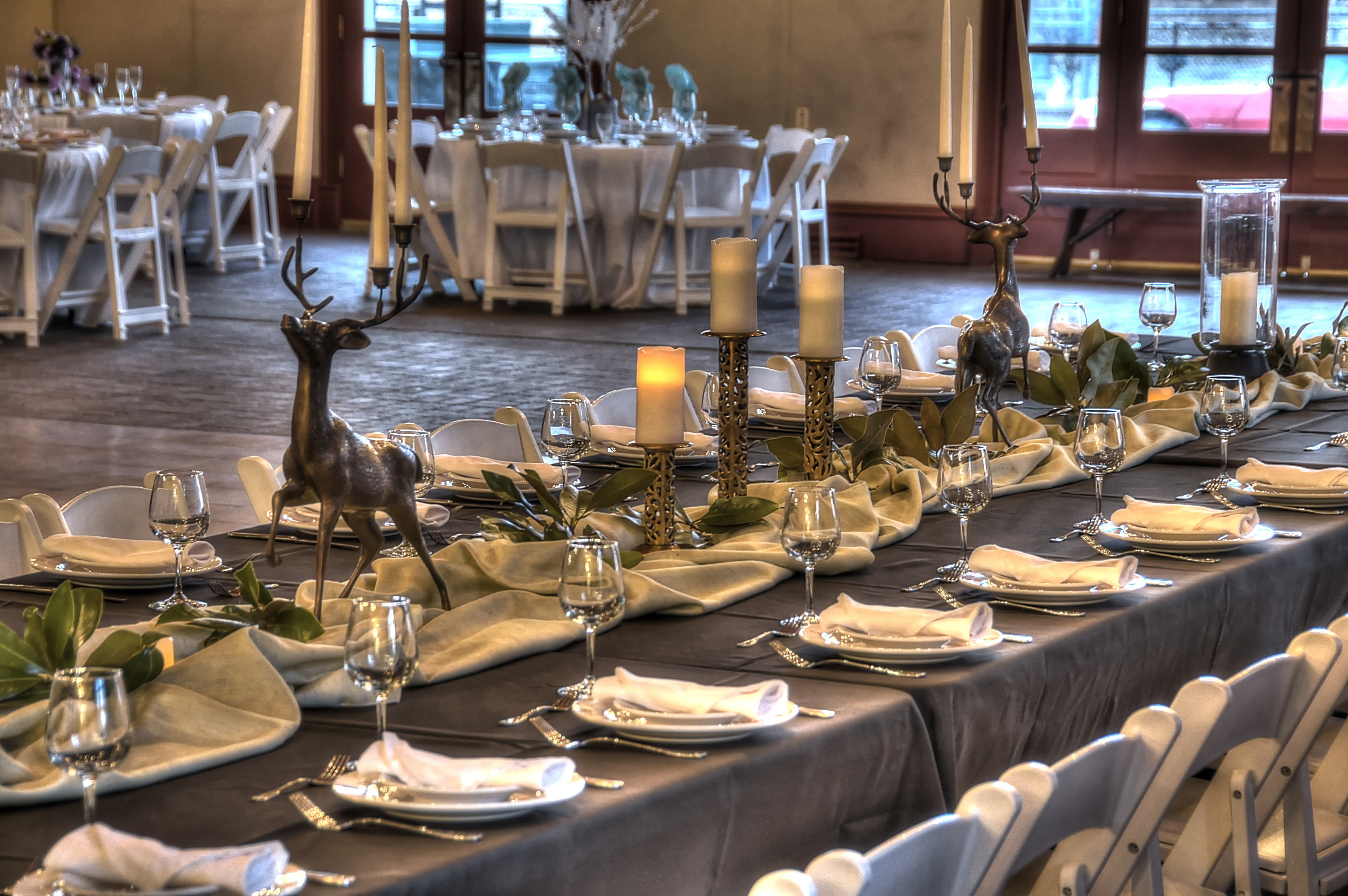 A beautifully decorated dining table with deer centerpieces and elegant table settings in a spacious venue.