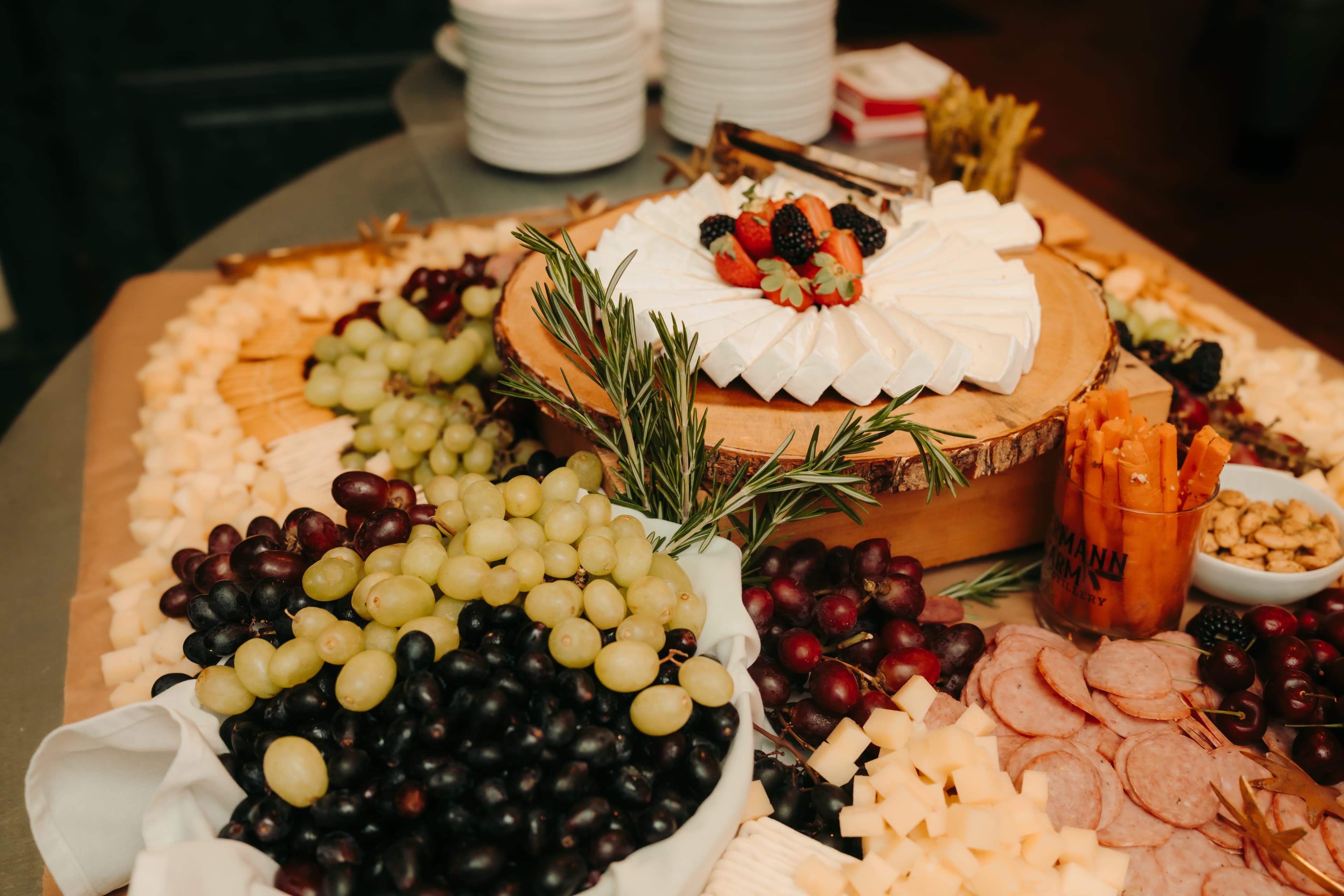 A beautifully arranged cheese and charcuterie board featuring various cheeses, fruits, and garnishes.