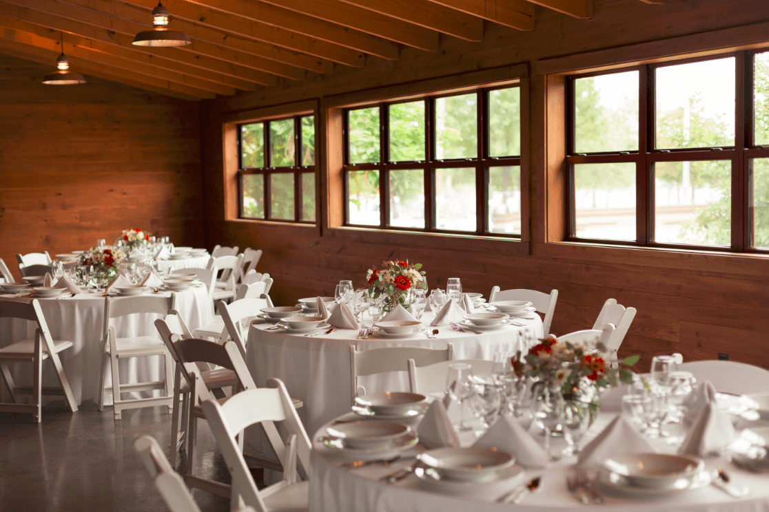 A beautifully arranged dining area with round tables set for a meal, featuring white tablecloths and floral centerpieces.