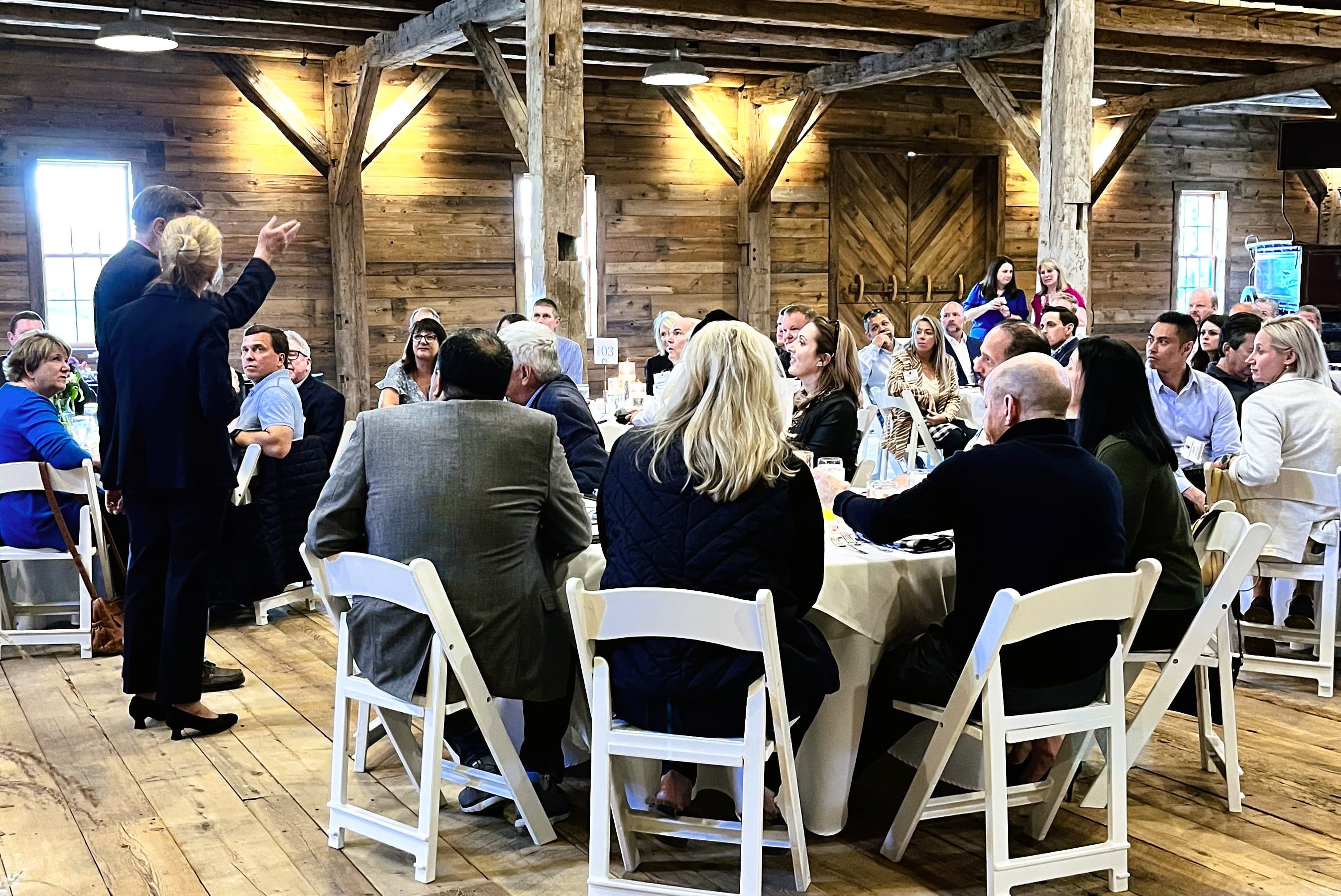 A speaker engages a large audience during an event in a rustic wooden venue.