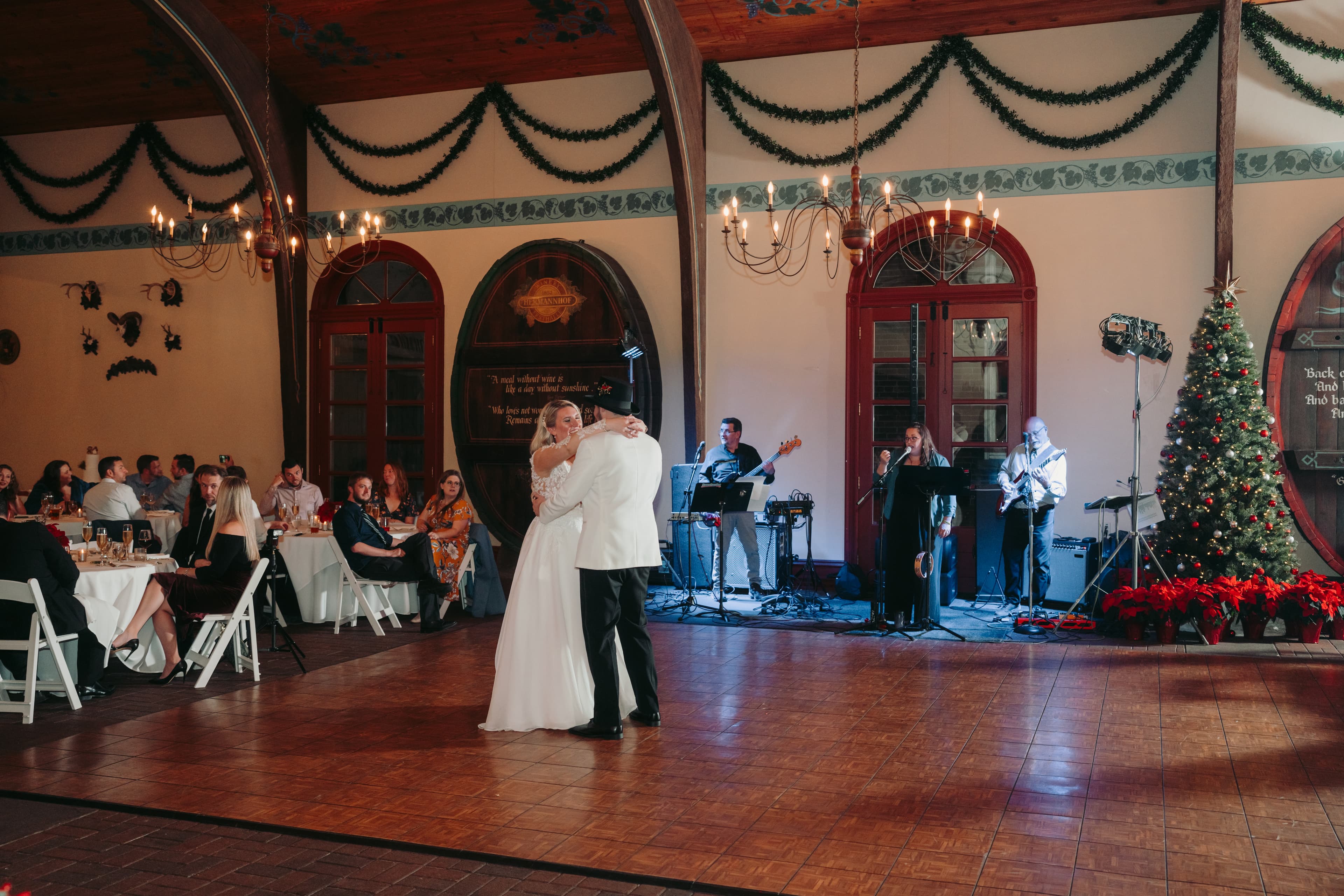 A bride and groom dance together in a festive venue while a live band performs in the background.