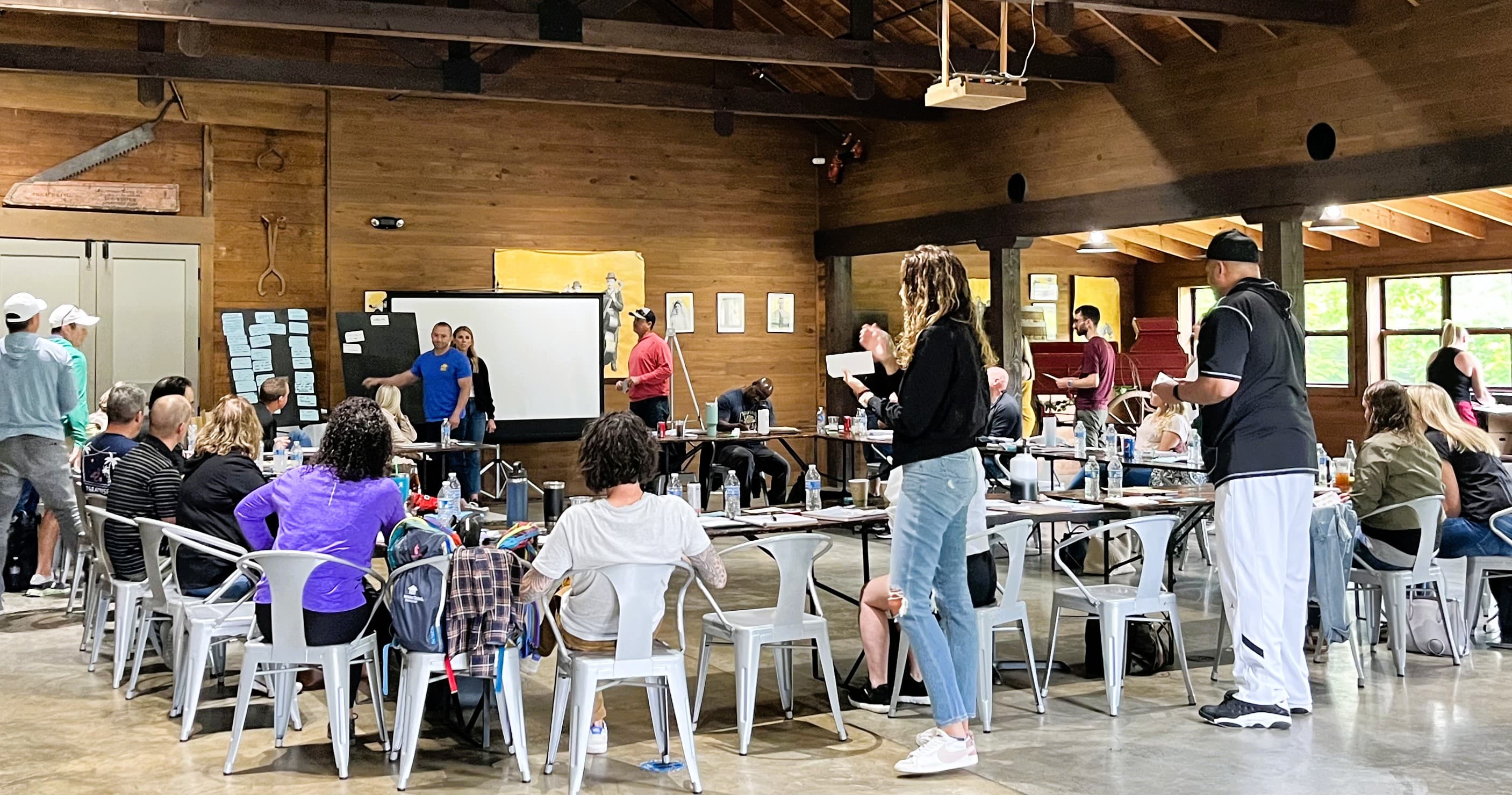 A group of people gathered in a room with tables, engaged in a discussion or activity.